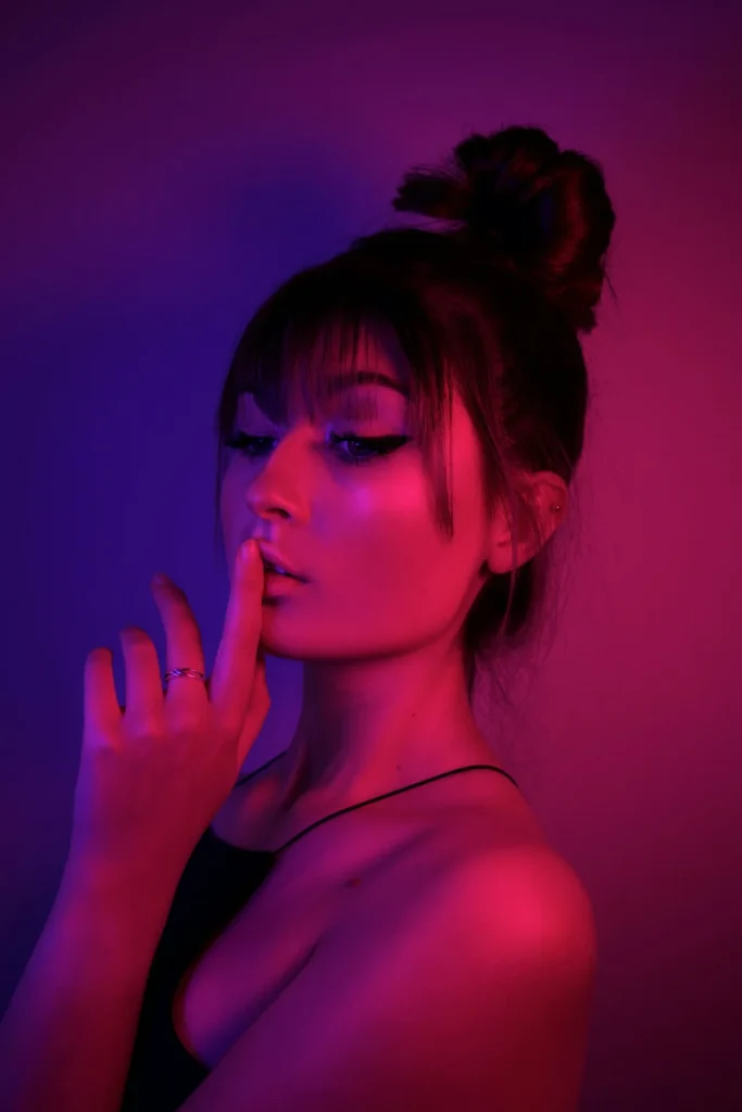 Hoher Dutt mit Pony und Augen-Make-up bei farbigem Licht