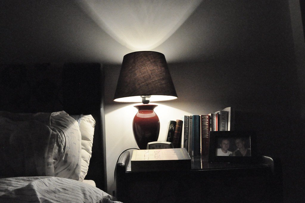 Nachttisch mit roter Lampe, Büchern und einem gerahmten Foto